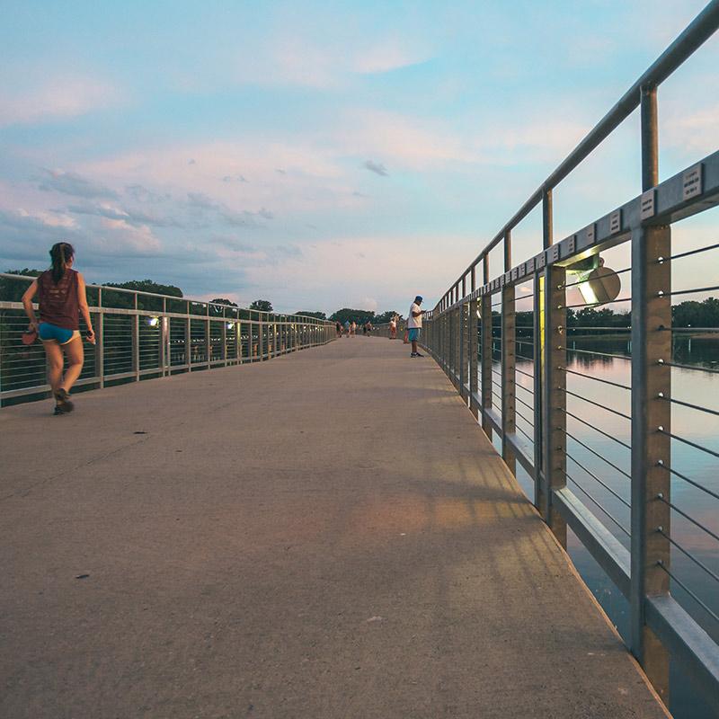 Drake student walking on the pedestrian bridge over Raccoon River near downtown Des Moines